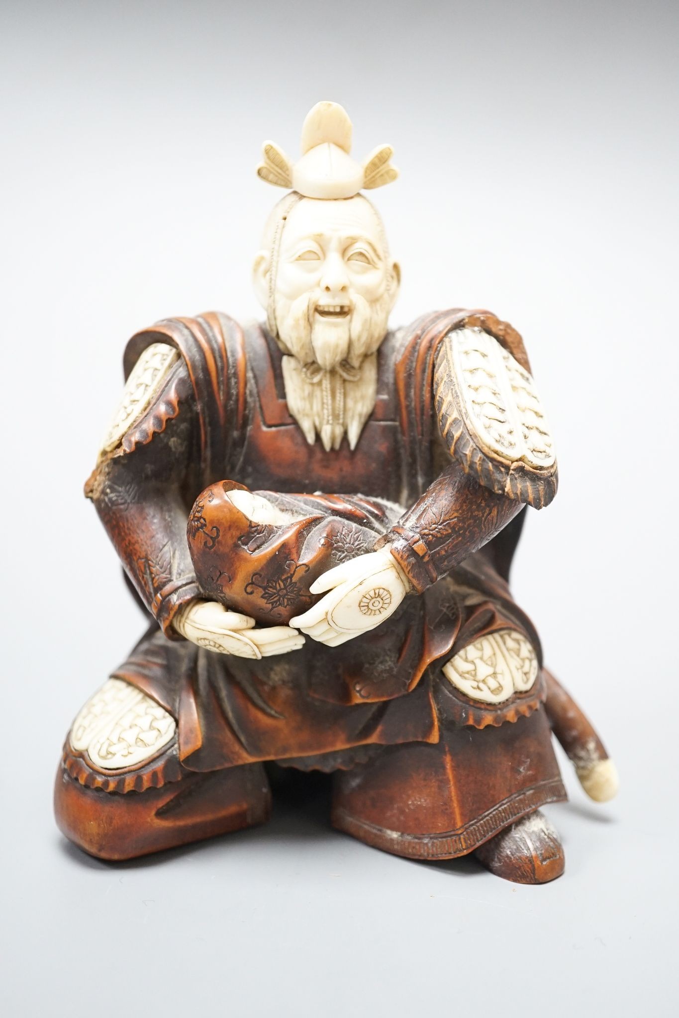 A Japanese wood and ivory okimono of a kneeling samurai holding a baby, Meiji period, unsigned, 12cm